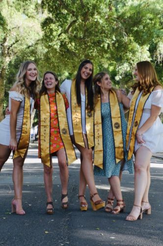 Graduate photo of 5 white women in dresses standing on the road.