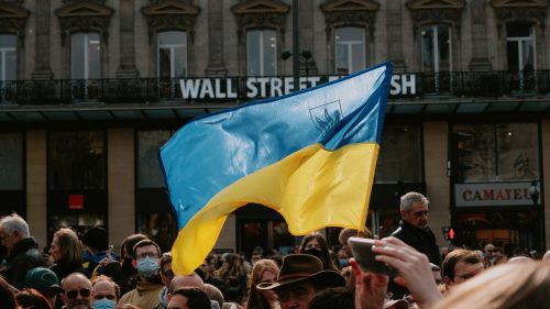 Ukranian flag above a crowd of people waves in front of Wall Street