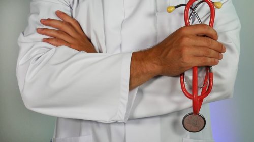 A person in a lab coat with their arms folded holding a stethoscope