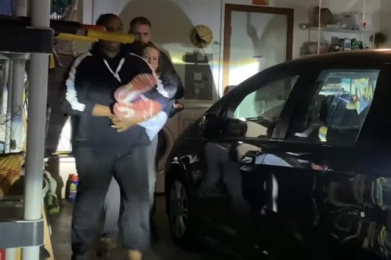 image of man and woman holding baby in garage